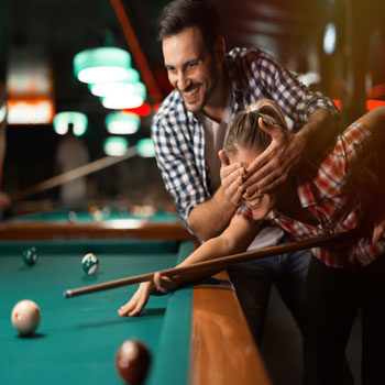 – Party guests playing a fun game of pool 